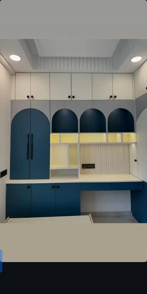 Storage wall with arched blue doors, open shelves and a study desk