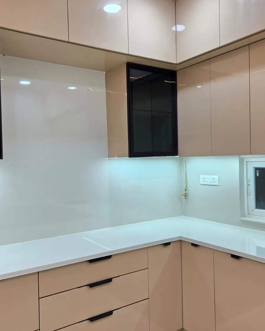 L-shaped modular kitchen with beige gloss shutters, tall wall cabinets and under-cabinet lights