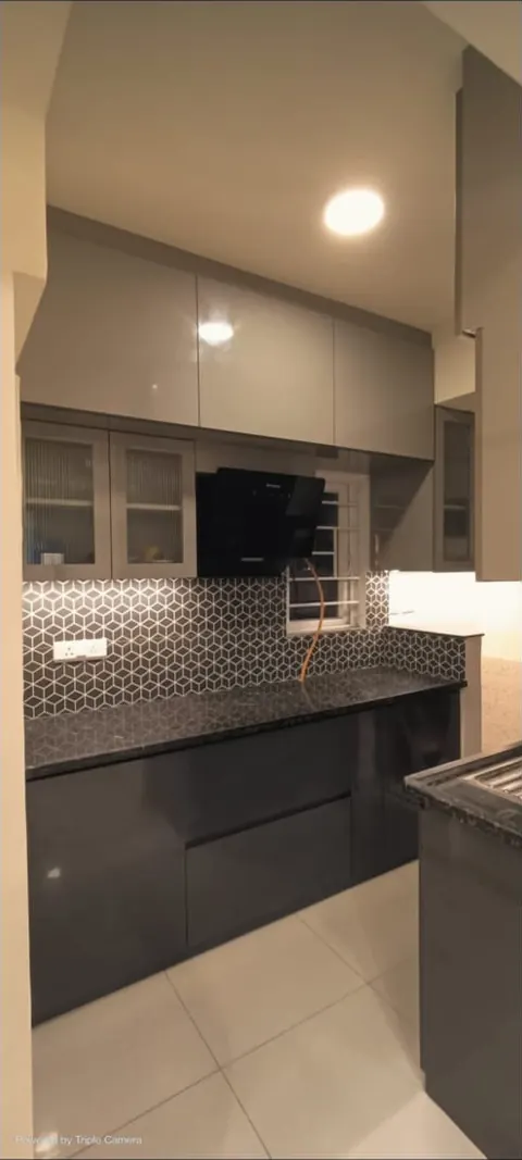 Grey modular kitchen with glass-front wall cabinets, a dark worktop and a patterned tile backsplash