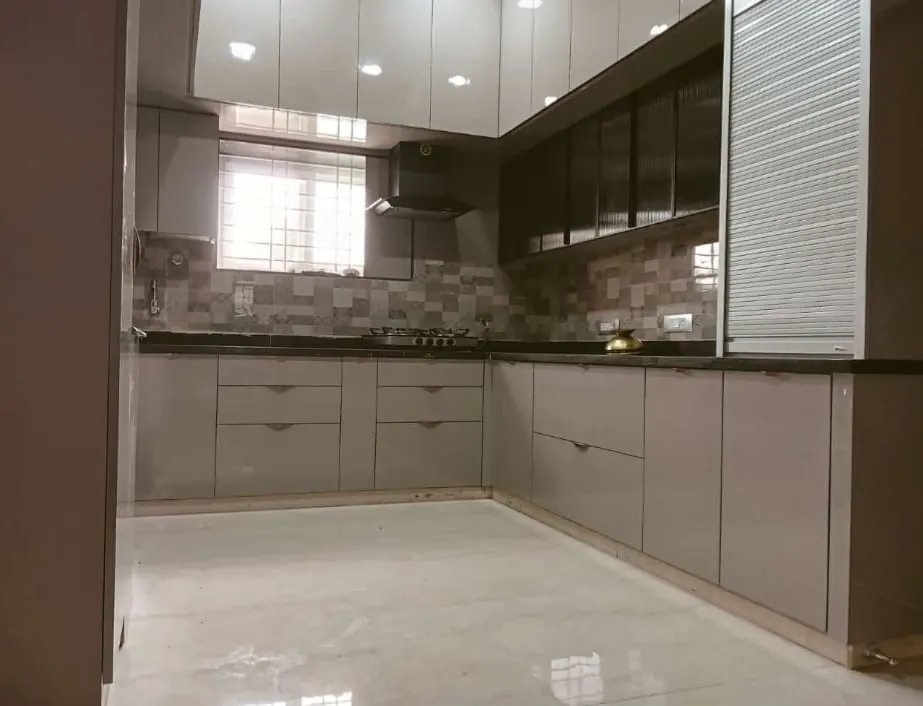 L-shaped kitchen with grey base units, glass-front wall cabinets and a tall unit with a roller shutter