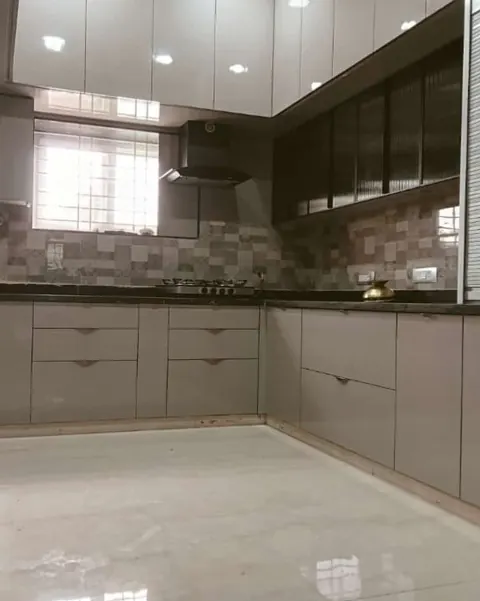L-shaped kitchen with grey base units, glass-front wall cabinets and a tall unit with a roller shutter